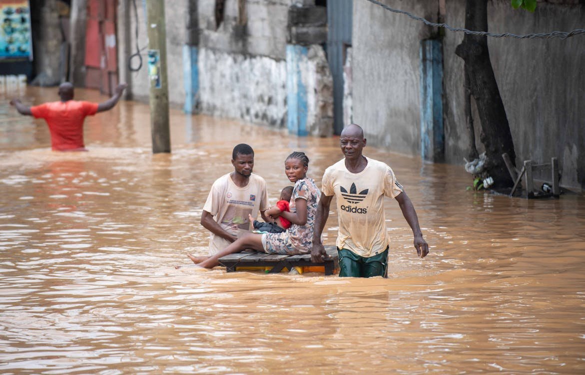 Residents make their way through a flooded street during heavy seasonal rains in Accra